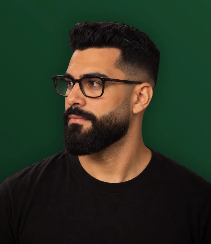 Homem de óculos com barba cheia que afina em direção ao cabelo
