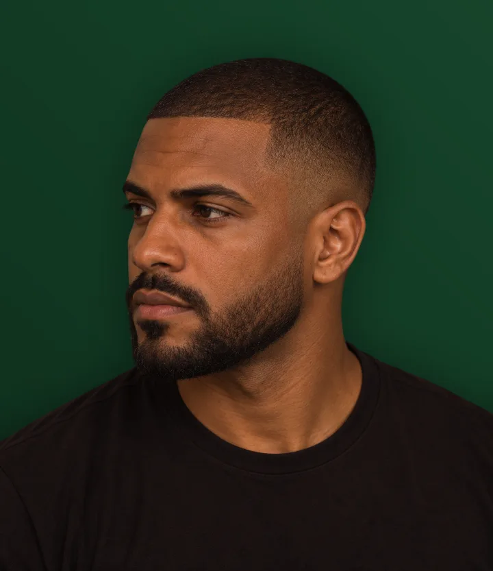 Homem de perfil com cabelo raspado baixo por igual e barba curta