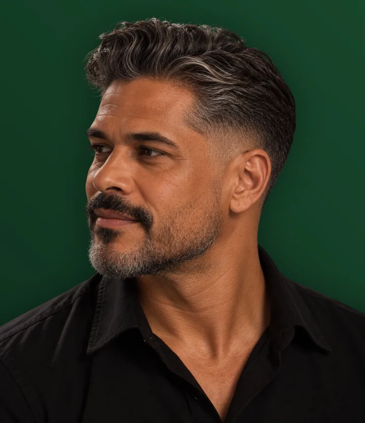 Homem grisalho de perfil com cabelo penteado para trás e laterais baixas